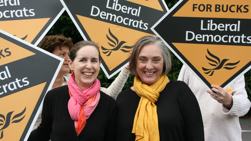 Christine and Susanne standing in front of Lib Dem sign Boards